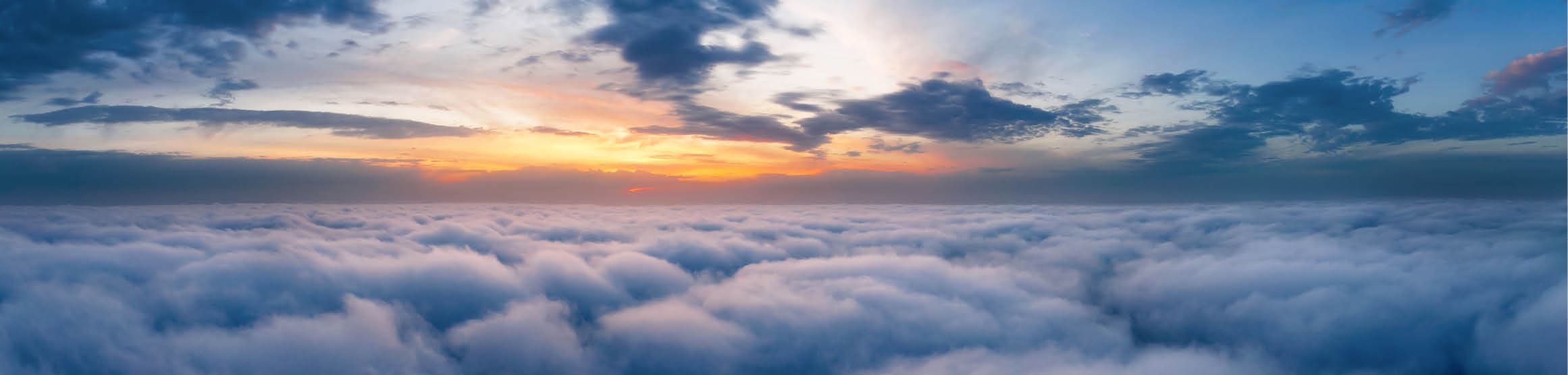 Beautiful dramatic sunset sky above fluffy clouds early in the morning from aerial drone view.